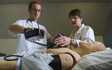 Nursing Faculty helping student with AED simulation