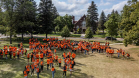 UJ students in orange shirts stand on Allen Field