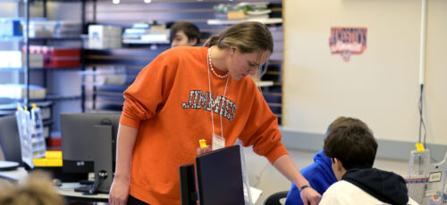 A woman points to something to help a student understand.