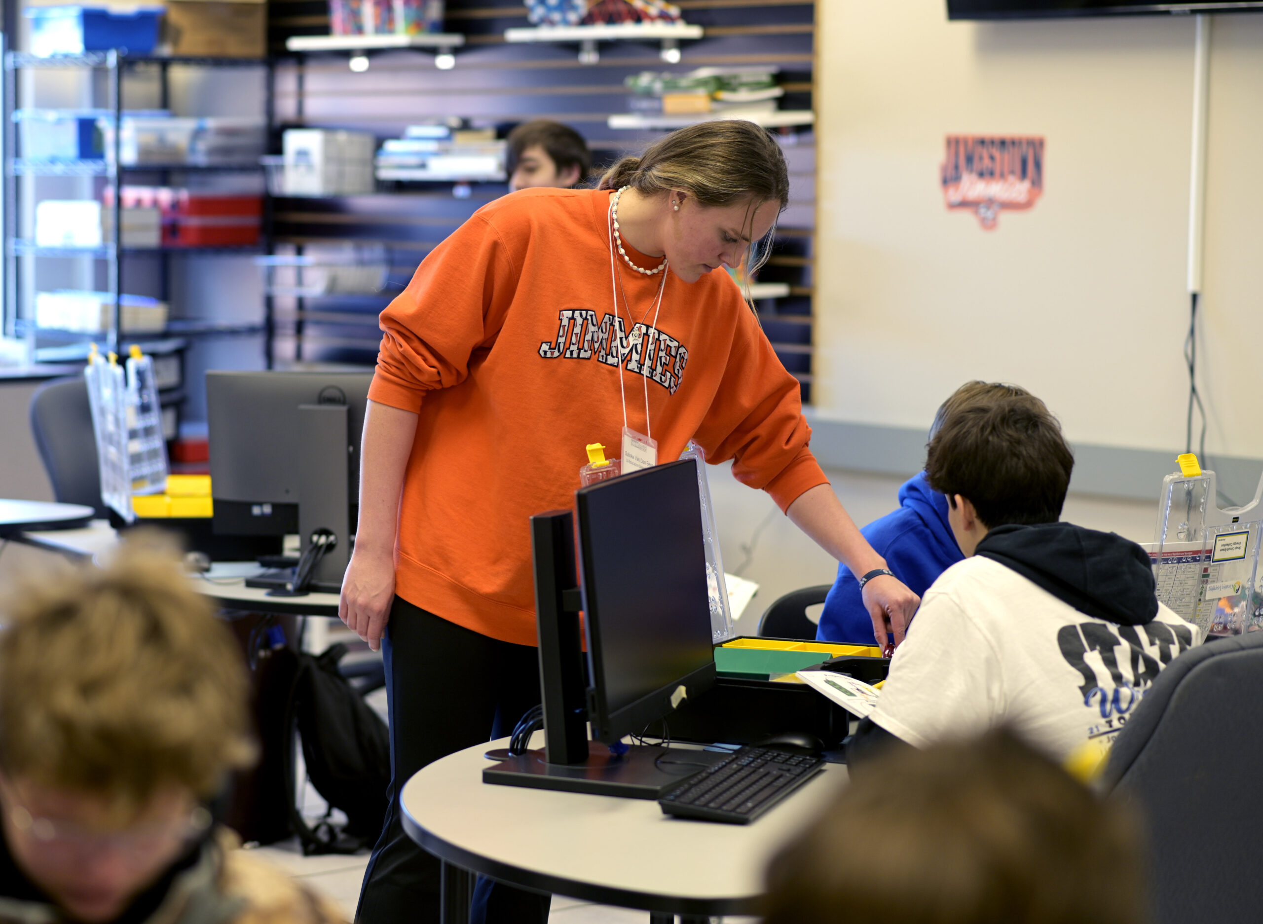 A woman points to something to help a student understand. 