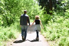 Tom and Judy walking hand in hand down a wooded path