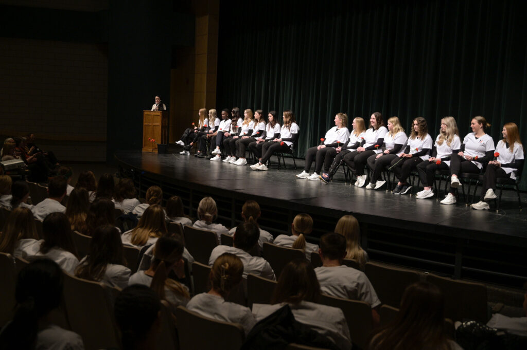 New Nursing students seated on stage during ceremony.