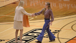 Two women shake hands in an awards ceremony.