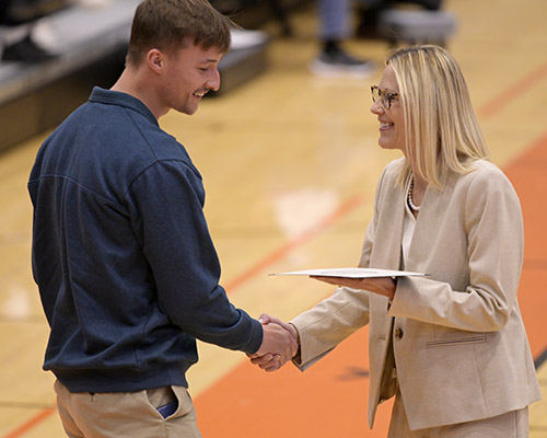 A man shakes hands with a woman at an awards ceremony. 