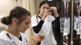 Nursing students work with IV equipment.
