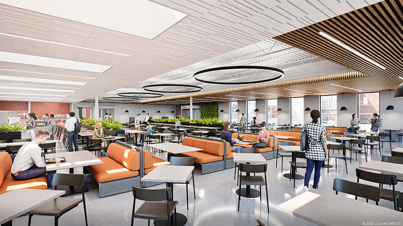 A large open cafeteria with tables, chairs, and orange booths around the room.