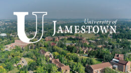 Aerial photograph of university campus showing trees and red-brick buildings, with white logo for 