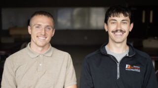 Two men smile for a photo.
