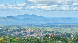 Landscape photo of Kenya with a city in the foreground and mountains in the background.