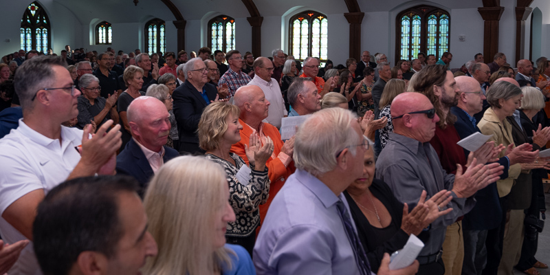 A crowd stands in a church and applauds.