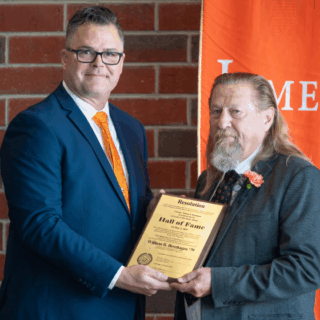 Will Bernhagen, Class of ’79, receives the University of Jamestown Alumni Hall of Fame award from Alumni Association President Matthew Gooding.