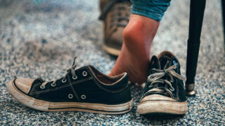 A set of shoes sits on the ground next to a child's feet.