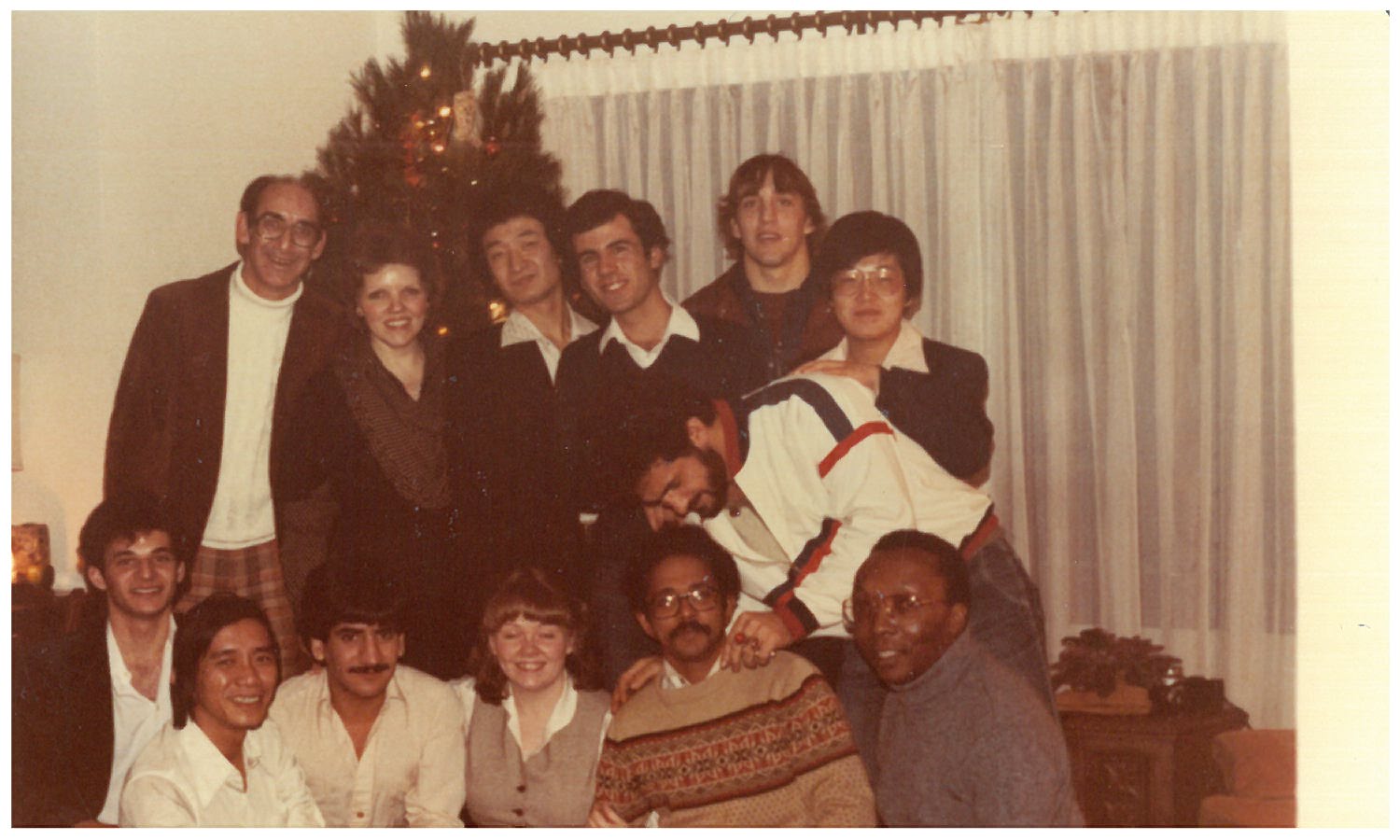 Holiday gathering with friends. A group gathers in front of a Christmas tree during a festive indoor event.