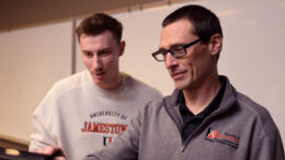 Two men look at a computer screen