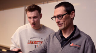 Two men look at a computer screen