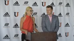Dr. Polly Peterson speaks at podium next to Athletic Director Austin Hieb