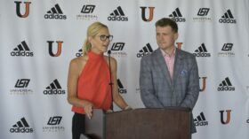 Dr. Polly Peterson speaks at podium next to Athletic Director Austin Hieb