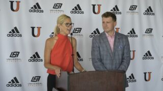 Dr. Polly Peterson speaks at podium next to Athletic Director Austin Hieb